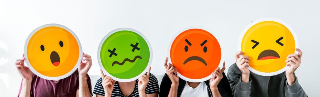 Cuatro personas sosteniendo emojis de diferentes emociones.